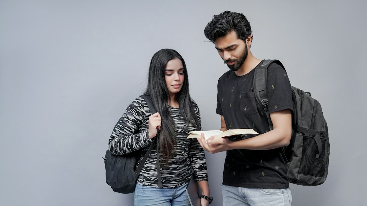 Two Indian students discussing concepts from a textbook